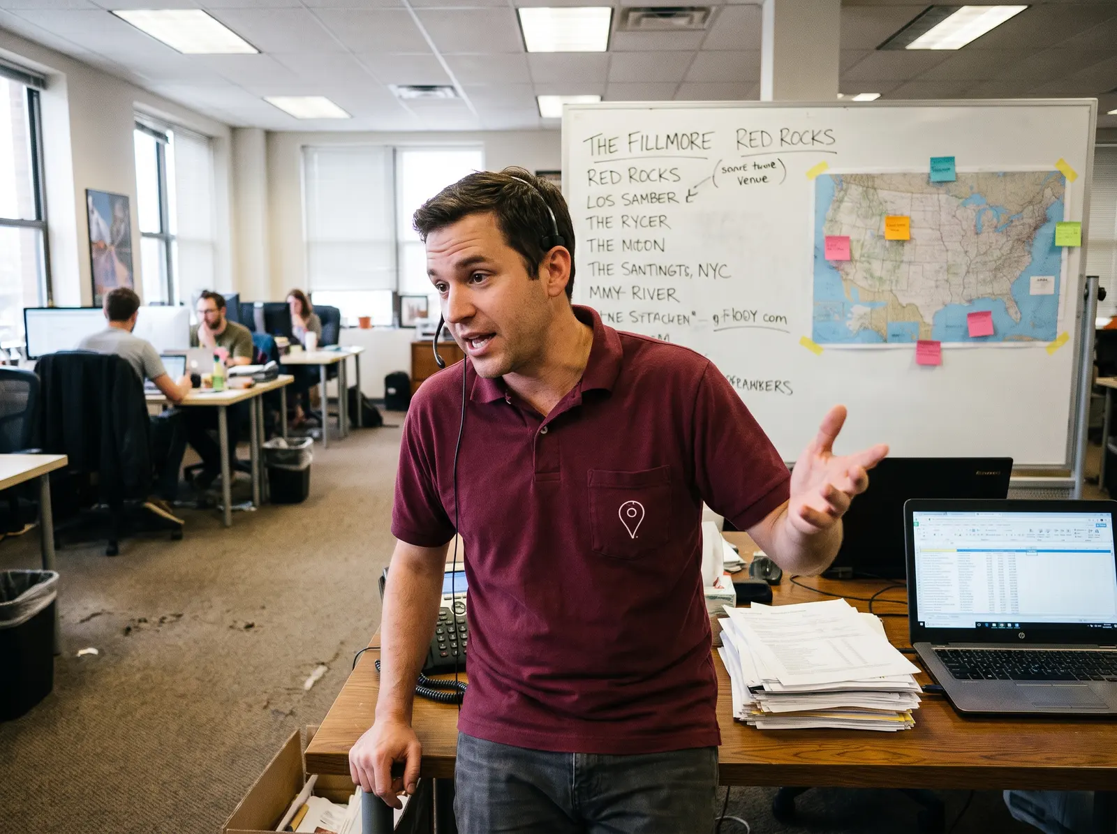 Two members of the Pinpoint team working at desks with headsets, calling venues.